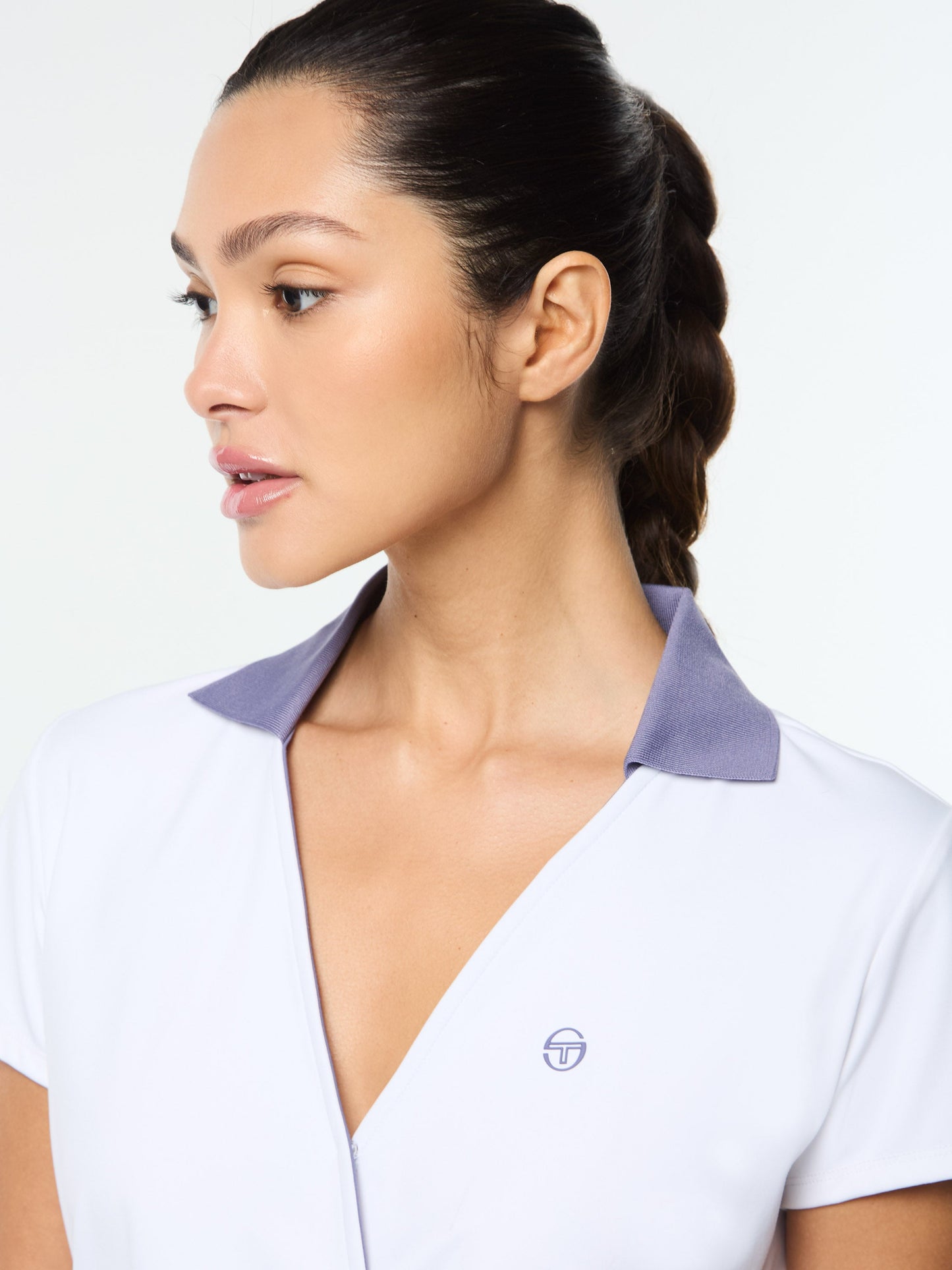 Woman wearing a white shirt with a purple collar against a light background