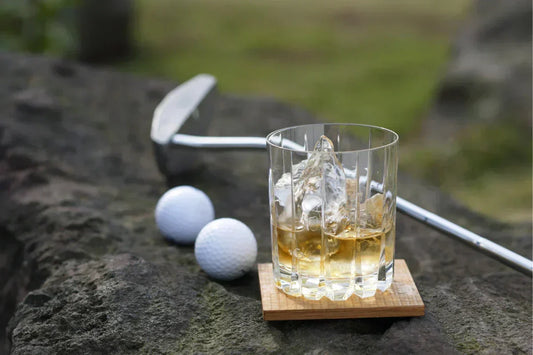 Glass of whisky with golf balls and a golf club