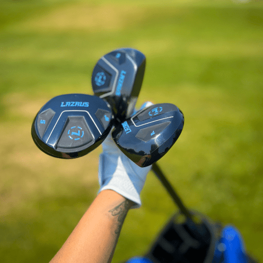 Golf clubs with 'Lazarus' branding held by a person on a grassy background