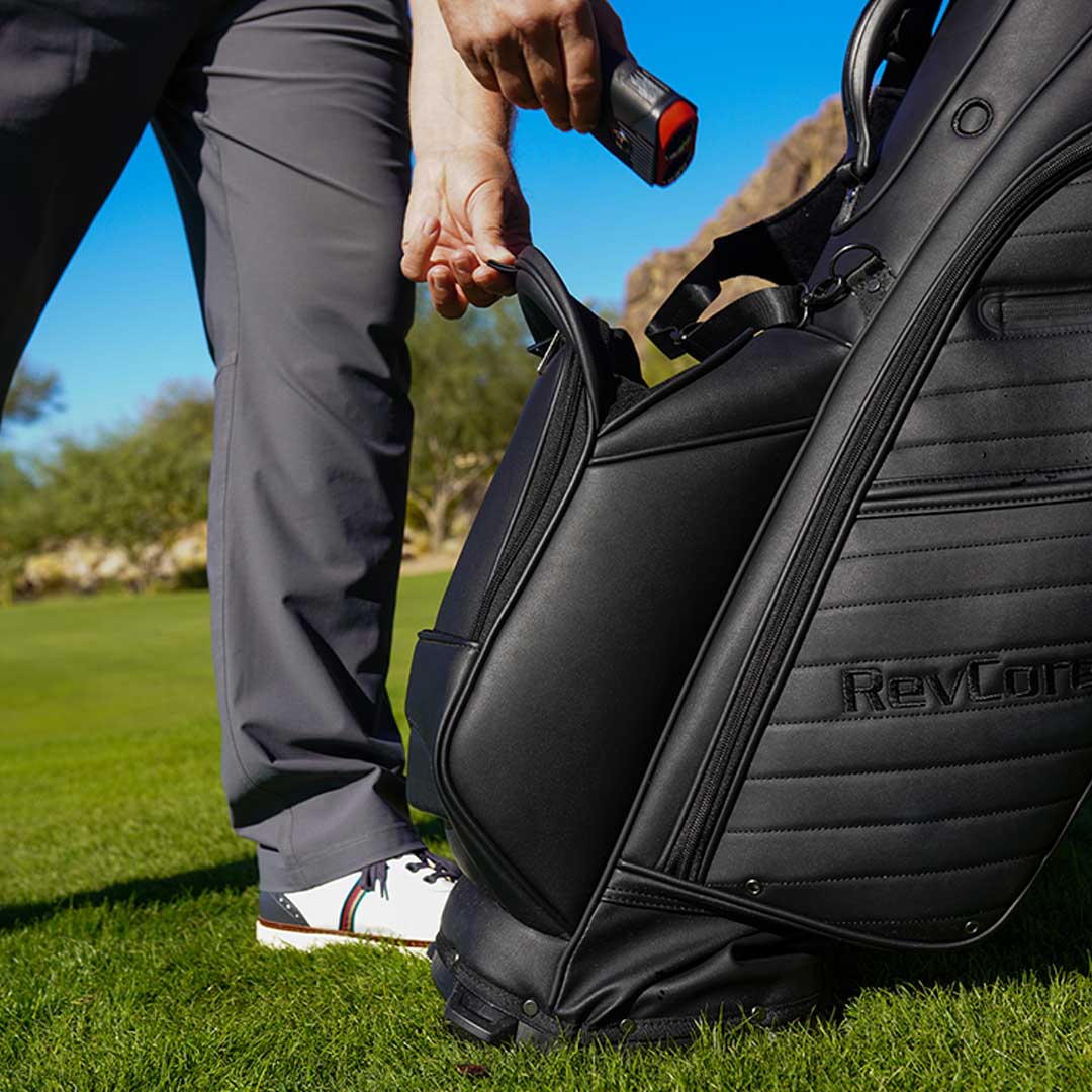 Person opening a golf bag with a club on a golf course