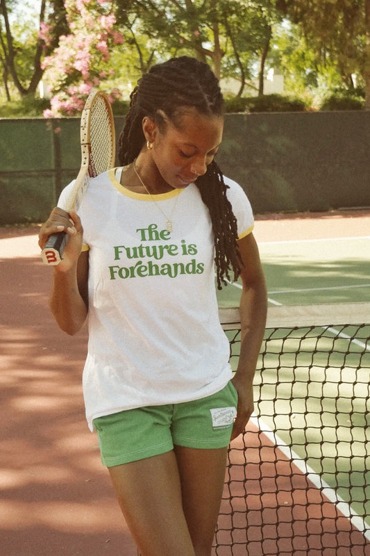 Person on a tennis court holding a racket with 'The Future is Forehands' shirt.