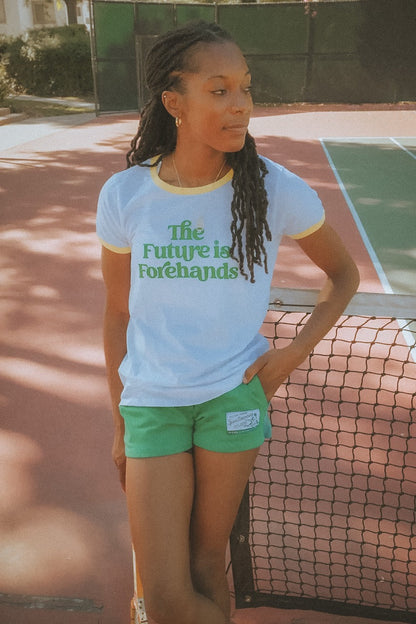 Person wearing a shirt with 'The Future is Forehands' on a tennis court