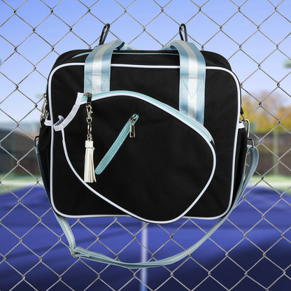 Black duffel bag with light blue straps and accents on a chain-link fence background