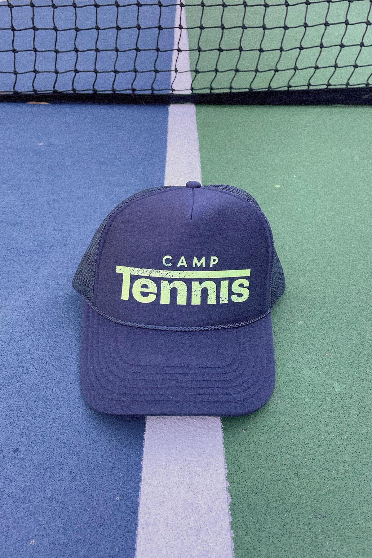 Blue cap with 'Camp Tennis' text on a tennis court
