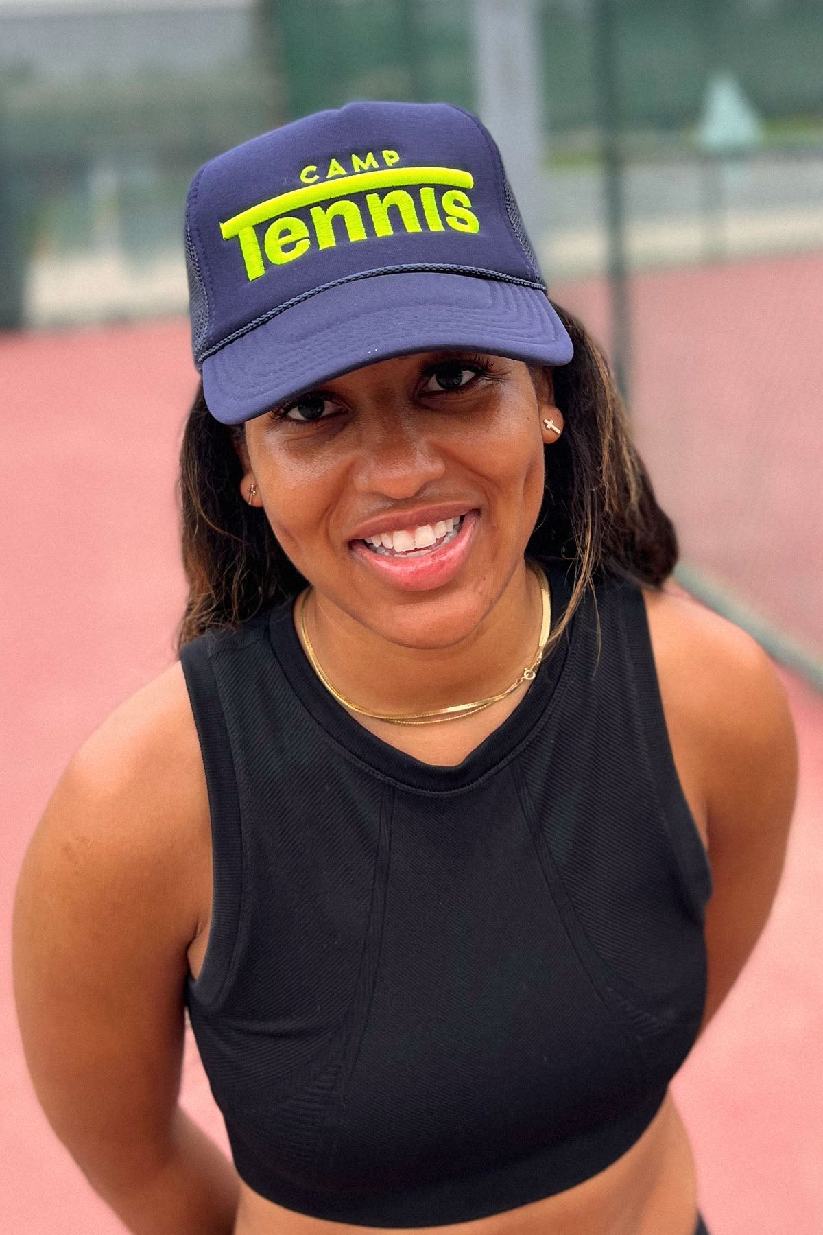 Person wearing a blue cap with 'Camp Tennis' text on a blurred background