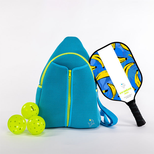 Blue pickleball bag with three green pickleballs and a blue pickleball paddle with banana design on a white background