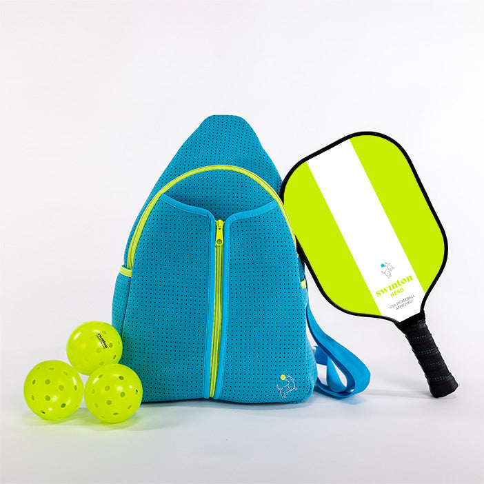 Blue pickleball bag with three green pickleballs and a pickleball paddle on a white background