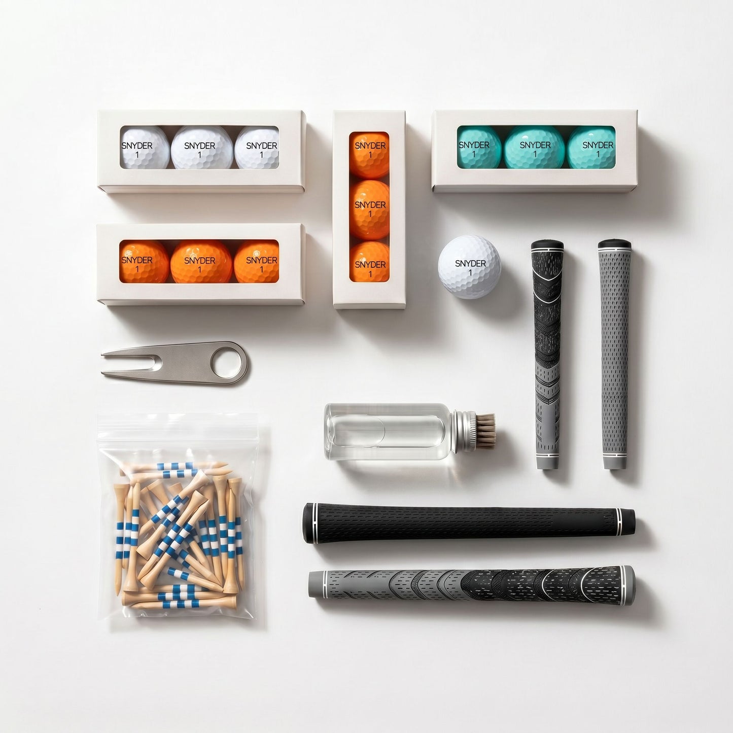 A flat-lay arrangement of a golf accessory kit on a white background, including several white boxes of Switzer golf balls in white, orange, and teal, a metal divot tool, a clear bottle with a gold cap, two black and gray textured grip covers, and a bag of blue-and-white checkered tees.