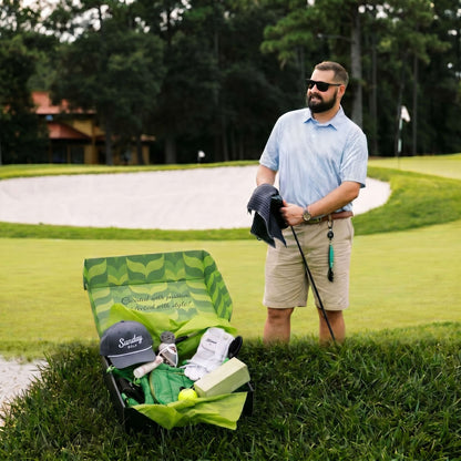 Man on golf course with open VolleyBird golf subscription box showing Sunday Golf hat and premium gear