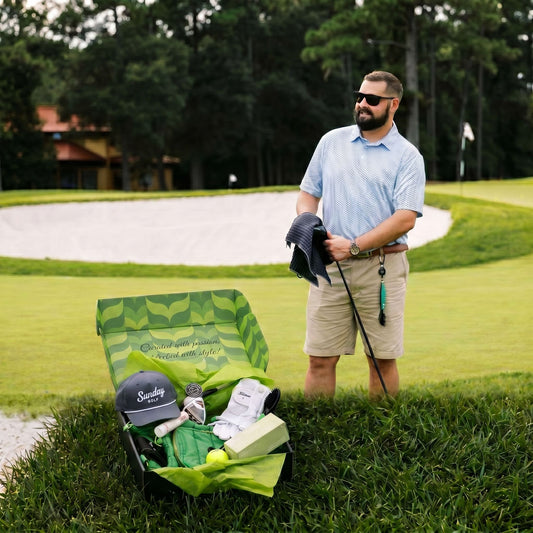 Man on golf course with open VolleyBird golf subscription box showing Sunday Golf hat and premium gear