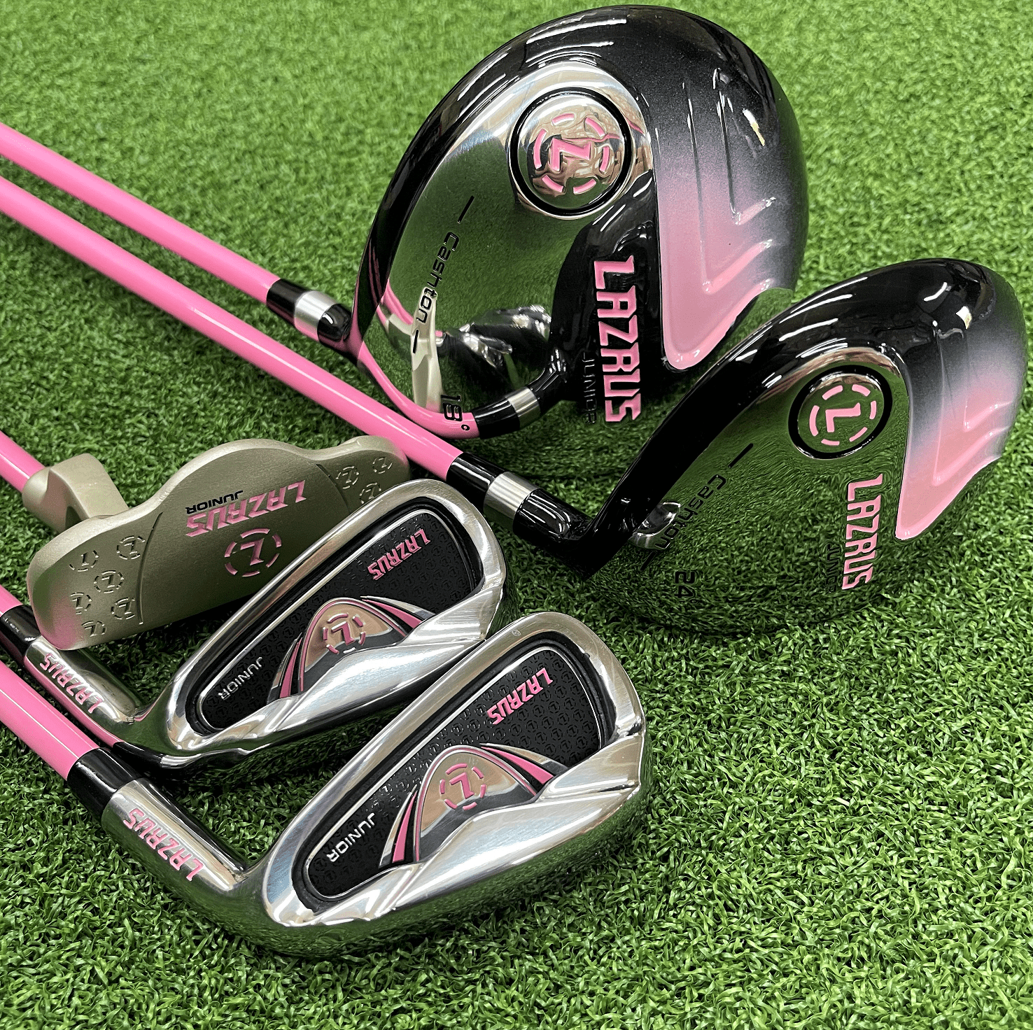 Golf clubs with pink and black design on a green grass background
