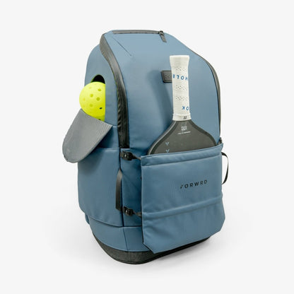 Blue backpack with a bottle and tennis ball inside on a white background
