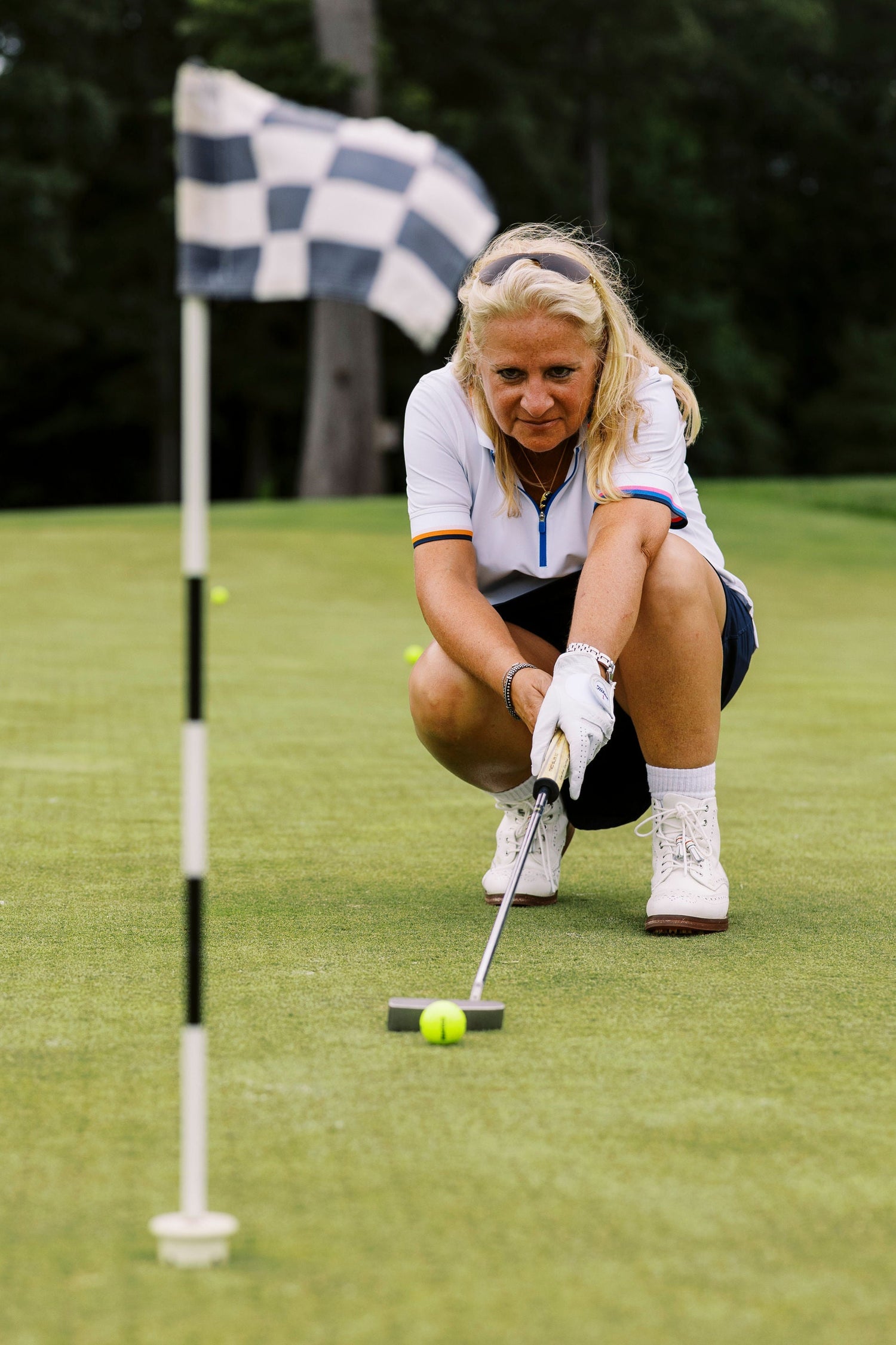 Woman on a golf course preparing to putt with a flag in the background