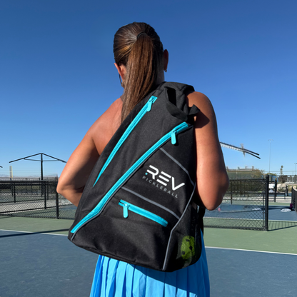 Person carrying a black and blue REV pickleball bag on a tennis court