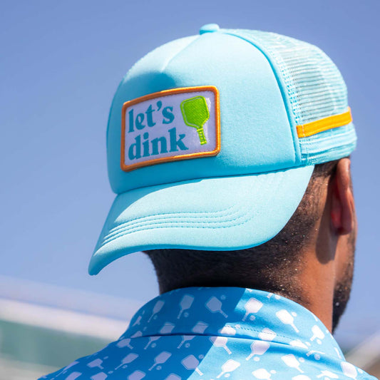 Light blue cap with 'let's dink' patch worn by a person against a clear blue sky.